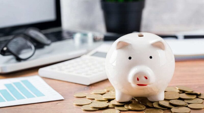 Foto de um cofrinho de porco com moedas em volta, simbolizando a diferença entre cooperativa de crédito e banco.